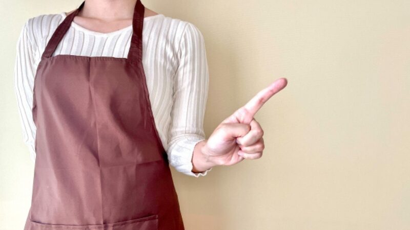 エプロン姿の人物が指を立て、調理や介護食づくりのポイントを伝えているイメージ写真。