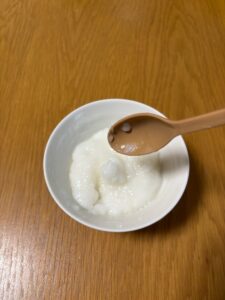 お茶碗に盛り付けたお粥ゼリーをスプーンですくい、傾けるとツルンと粥ゼリーが落ちた写真。