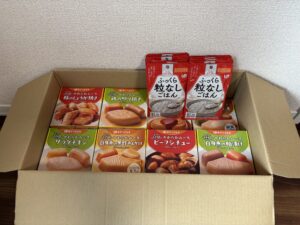 エバースマイルのやわらかムース食（主菜30品）とふっくら粒なしごはん10袋が段ボールに入っている写真
