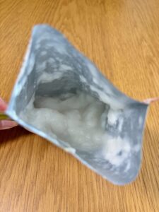 キユーピー「なめらかごはん」のパウチを開封した状態。銀色のパッケージの中に白くとろとろした中身が見える
