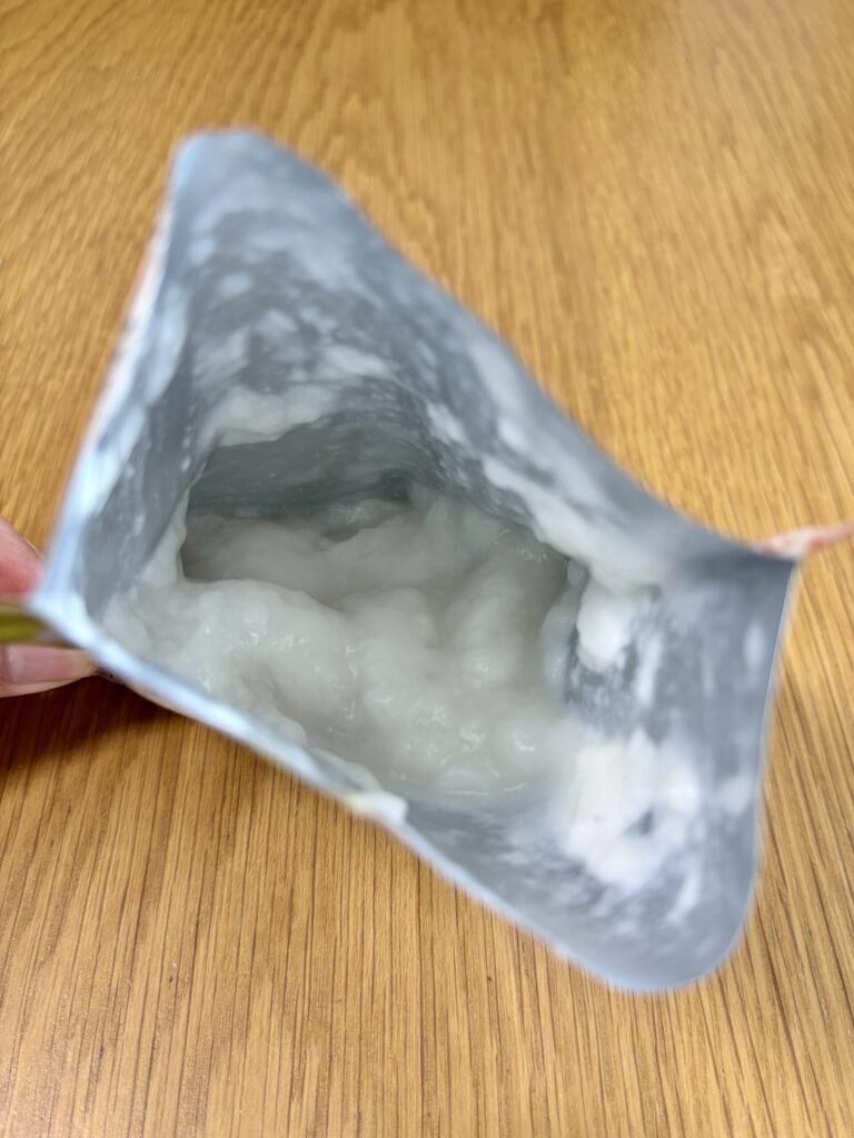 キユーピー「なめらかごはん」のパウチを開封した状態。銀色のパッケージの中に白くとろとろした中身が見える