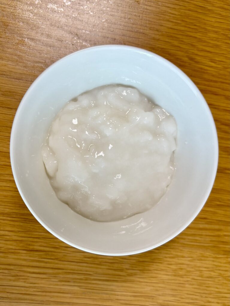 キユーピー「なめらかごはん」を白いお茶碗に盛り付けた写真。粒のないなめらかな白色で、透明感のあるとろとろした見た目