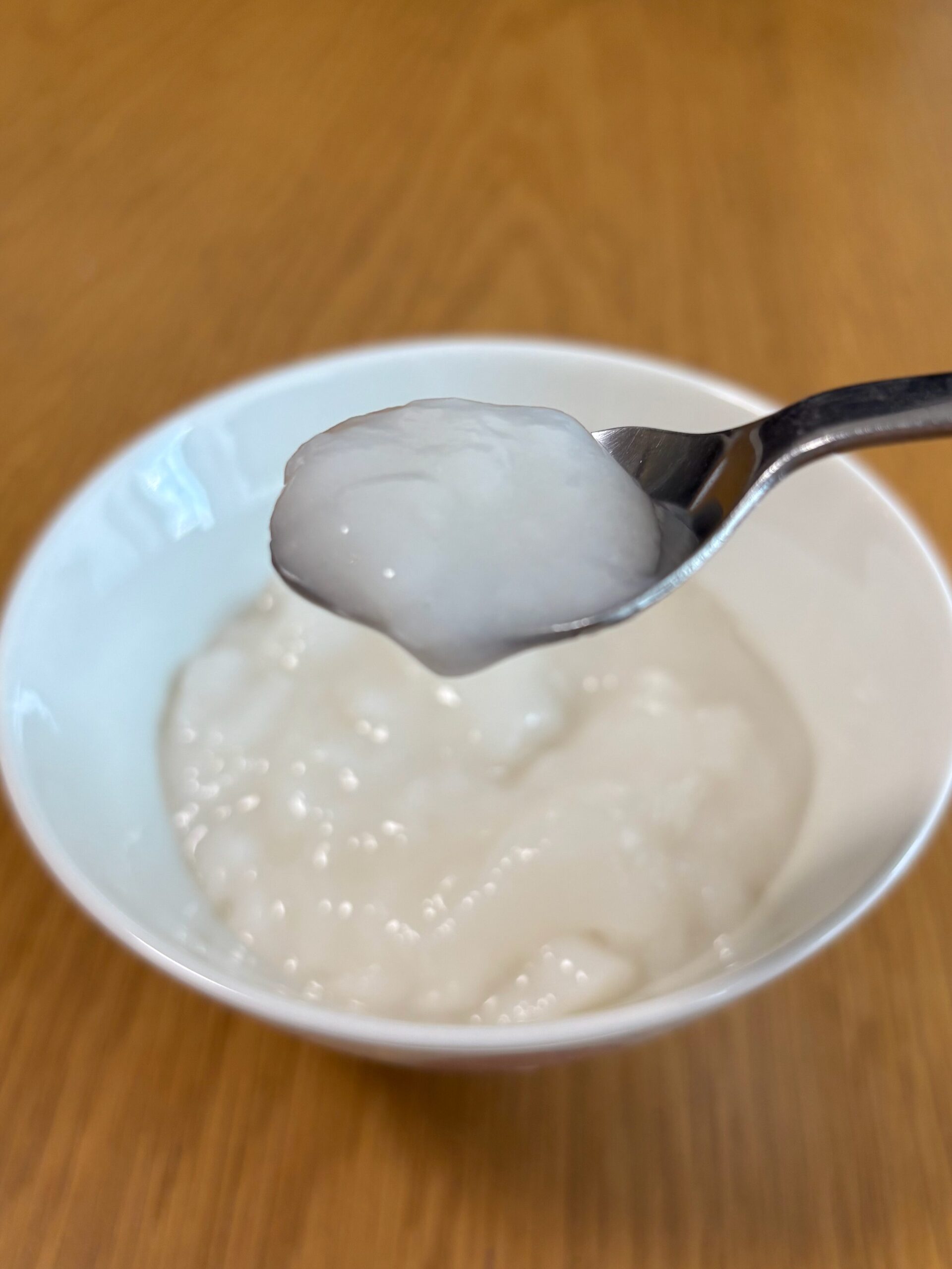 キユーピー「なめらかごはん」をスプーンですくった写真。常温の状態でとろーっとした柔らかい食感がわかる