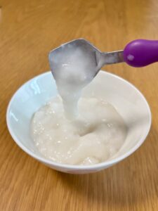 キユーピー「なめらかごはん」をのせたスプーンを傾けたところ。とろーっと流れ落ちる様子がわかる