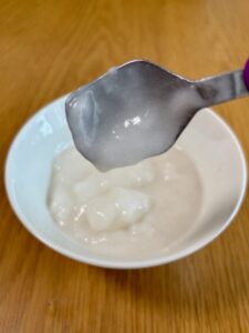 温めた、キユーピー「なめらかごはん」をのせ、スプーンを傾けた写真。スプーンにほとんど残らず、のどへの張り付きが少ないことがわかる。
