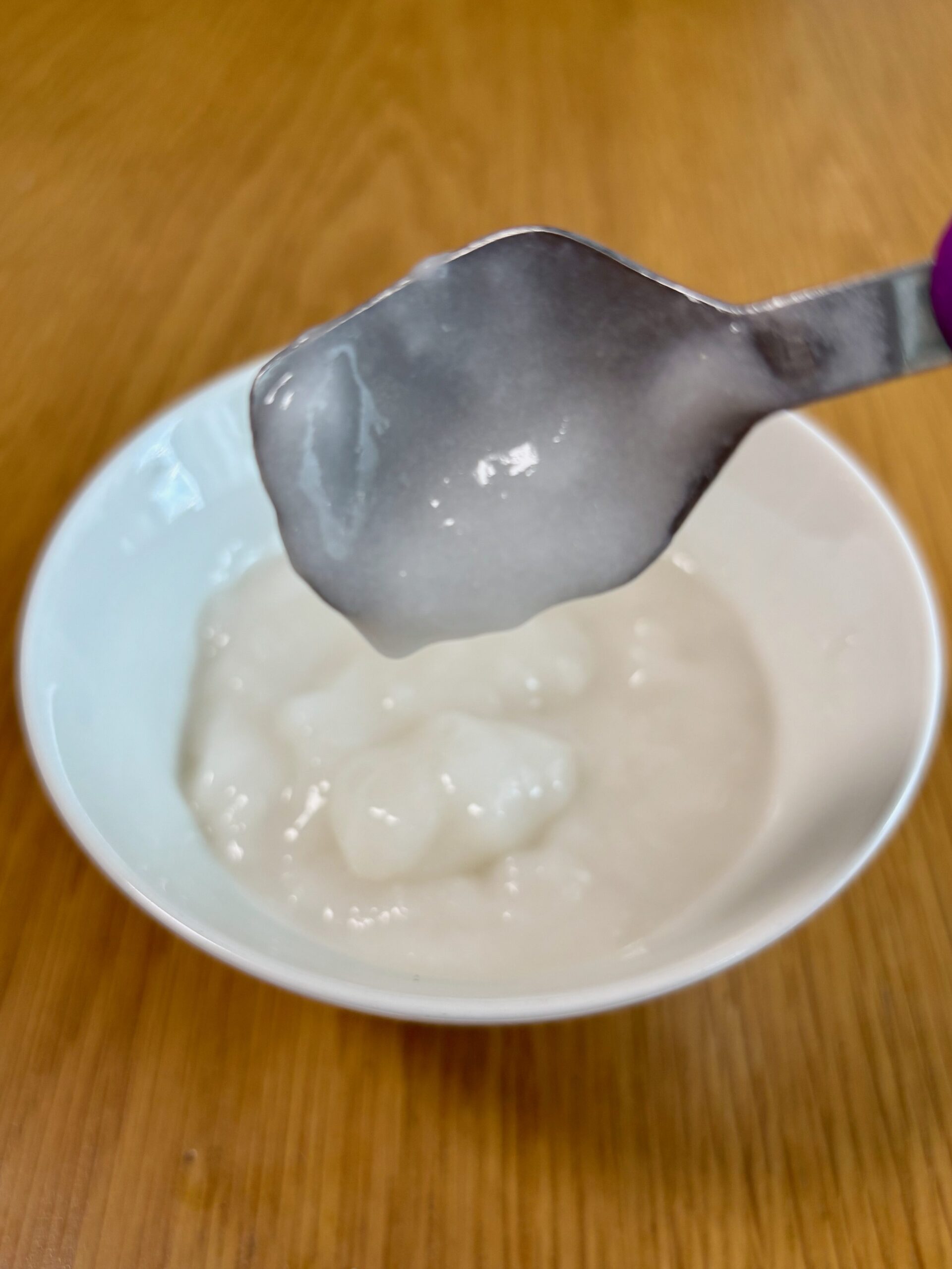 温めた、キユーピー「なめらかごはん」をのせ、スプーンを傾けた写真。スプーンにほとんど残らず、のどへの張り付きが少ないことがわかる。