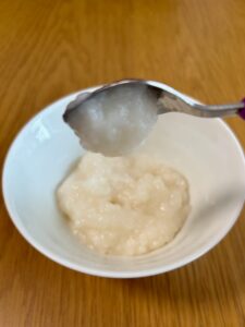 アサヒ「なめらかごはん」をスプーンですくい、傾けた状態。もったりしているのですぐには落ちず、５秒後くらいに落ちる。