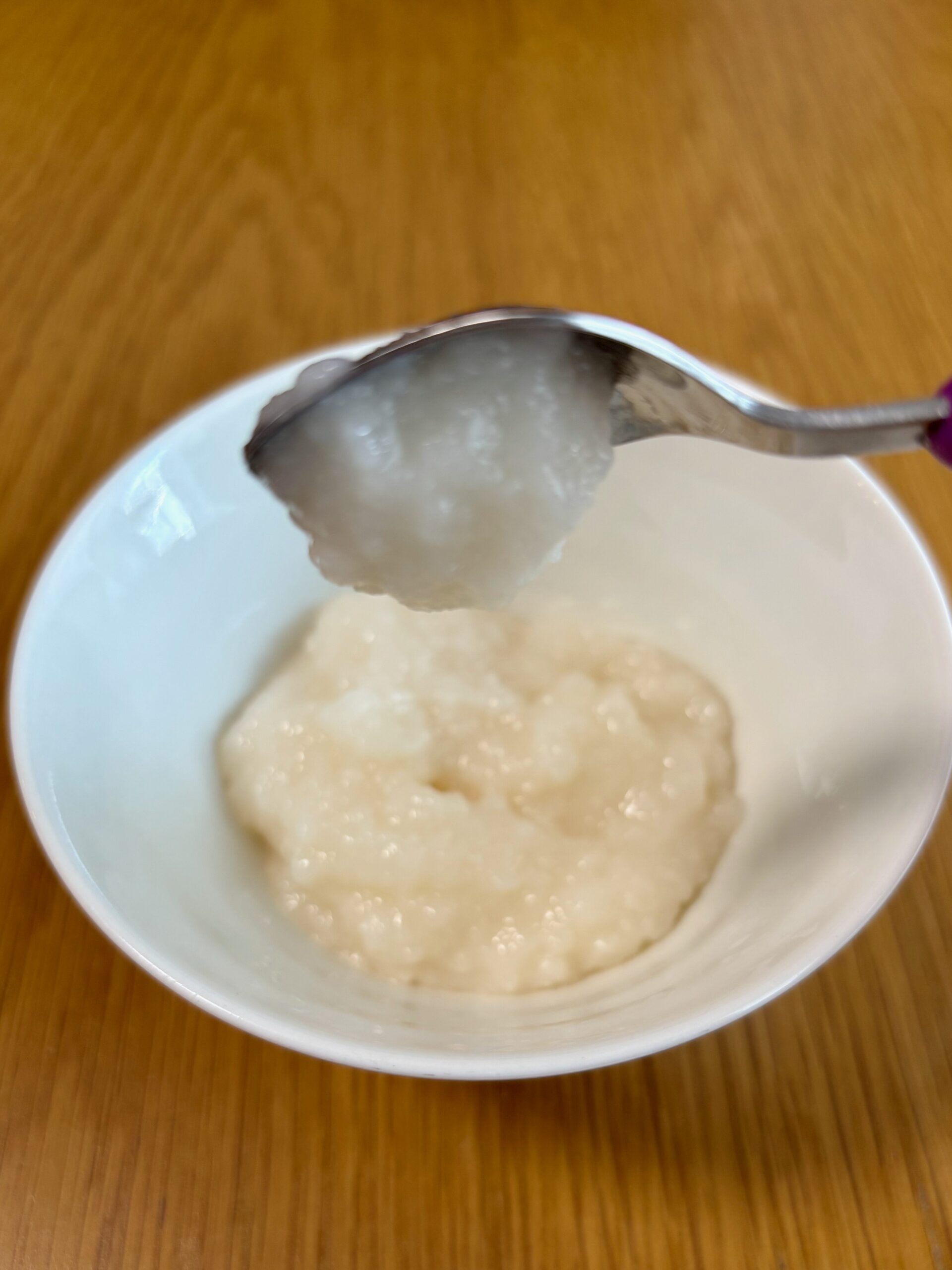 アサヒ「なめらかごはん」をスプーンですくい、傾けた状態。もったりしているのですぐには落ちず、5秒後くらいに落ちる。