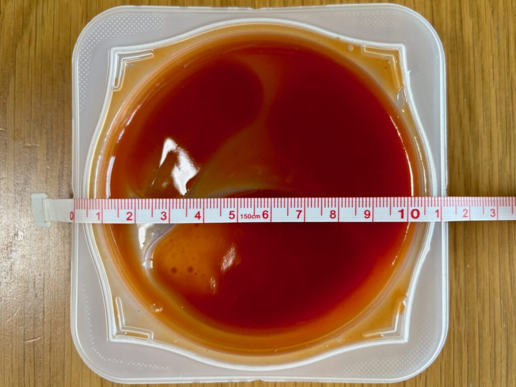 メジャーでエバースマイル トマトソースオムレツの容器の直径を測っている写真。直径は約11.5cm。