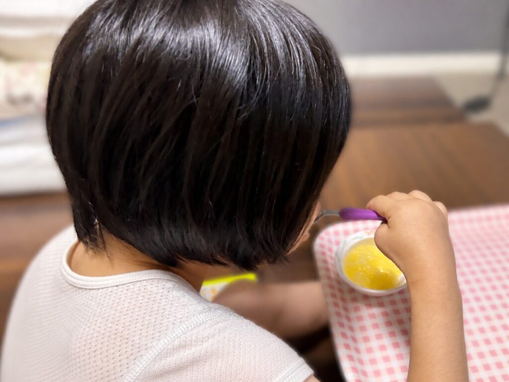 娘がオレンジジュースのムース食を食べている様子。