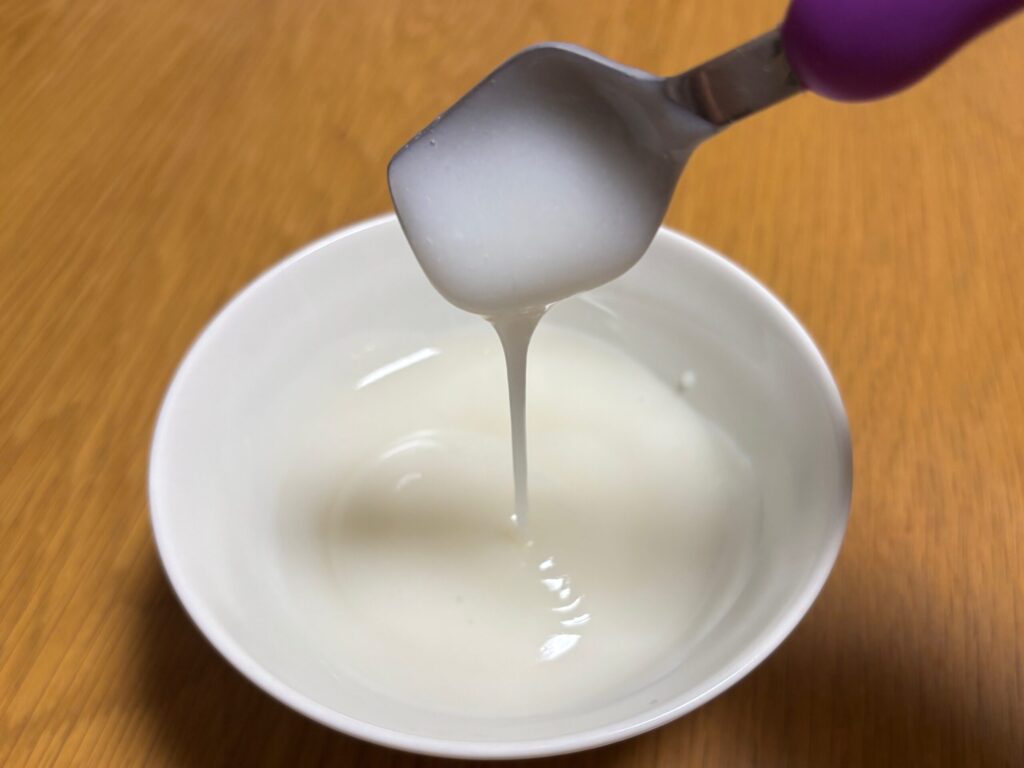 お茶碗に液状化したごはんを盛り付け、スプーンを傾けるとトロトロと落ちている様子。