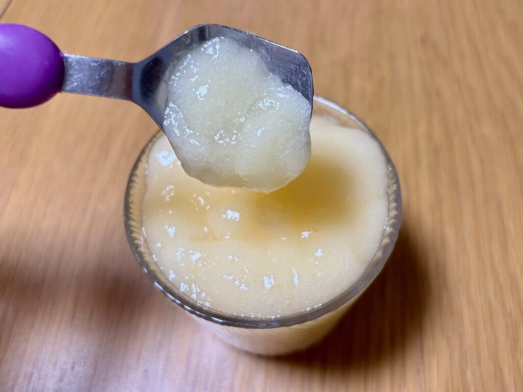 ミキサーゲル3gで作ったオレンジジュースのムース食をスプーンですくい、つるんと滑り落ちる様子