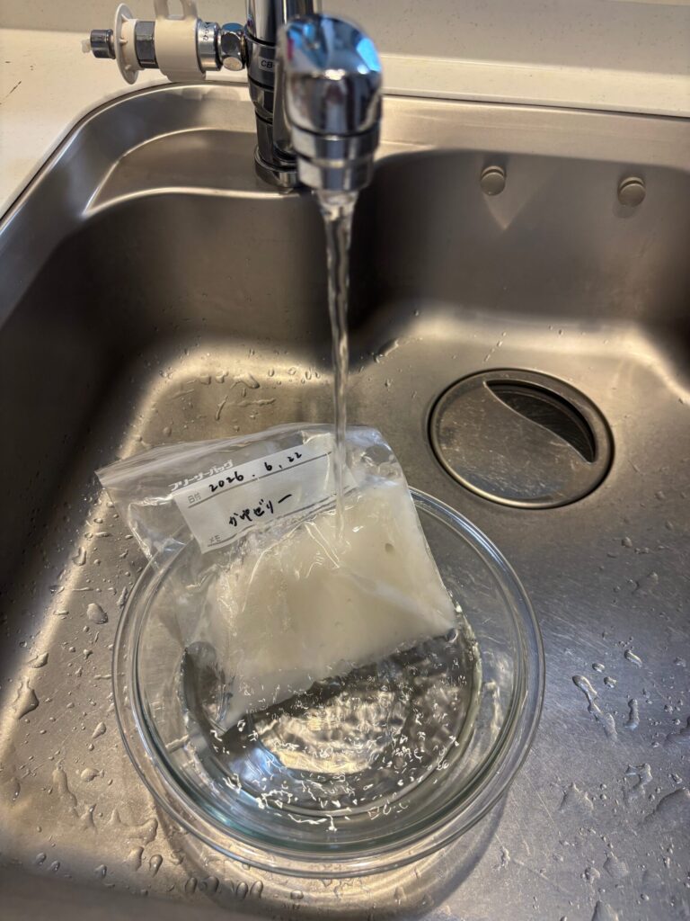 フリーザーバッグの周りを流水で溶かしてお粥ゼリーを取り出しやすくしている写真