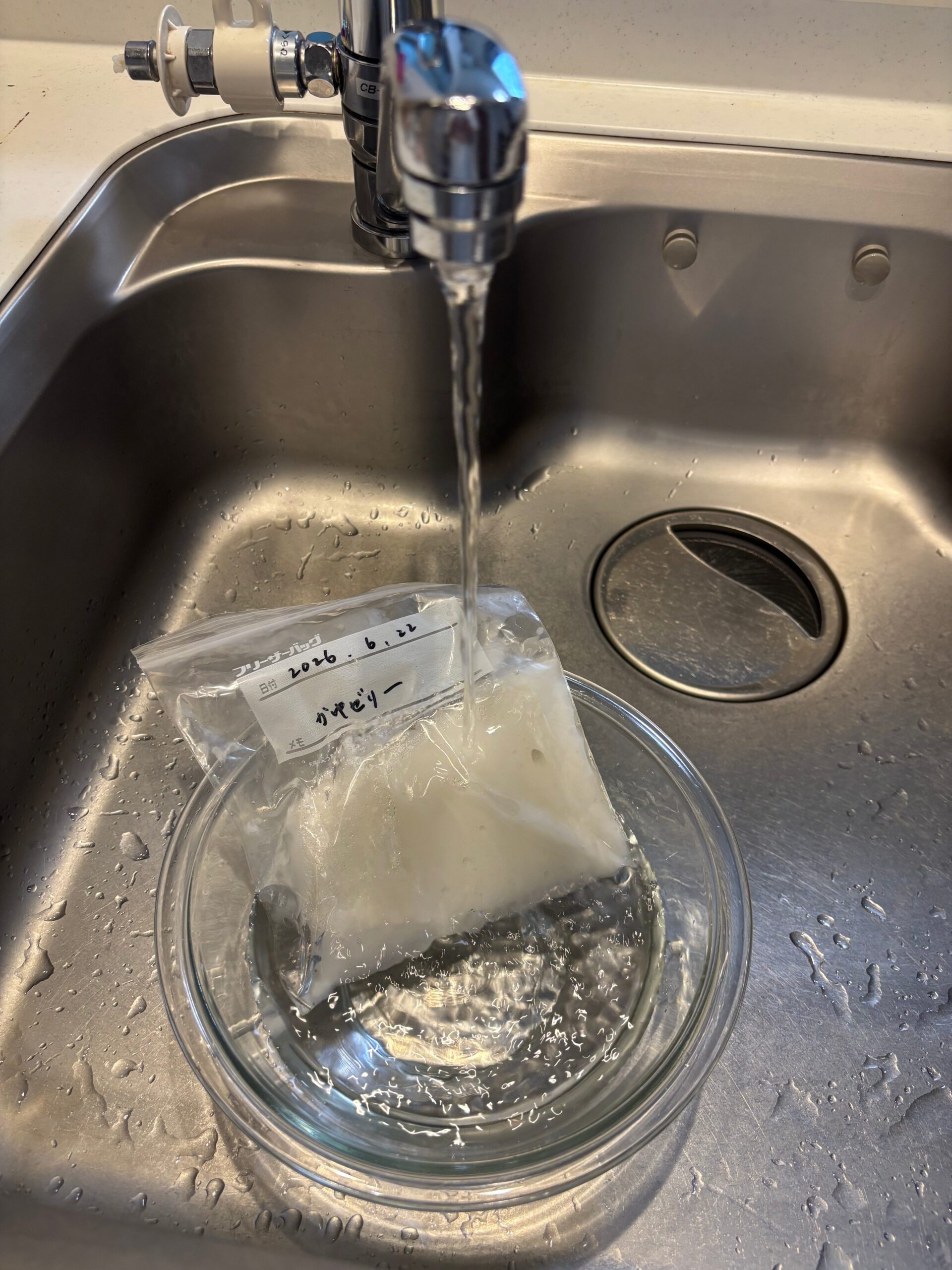 フリーザーバッグの周りを流水で溶かしてお粥ゼリーを取り出しやすくしている写真
