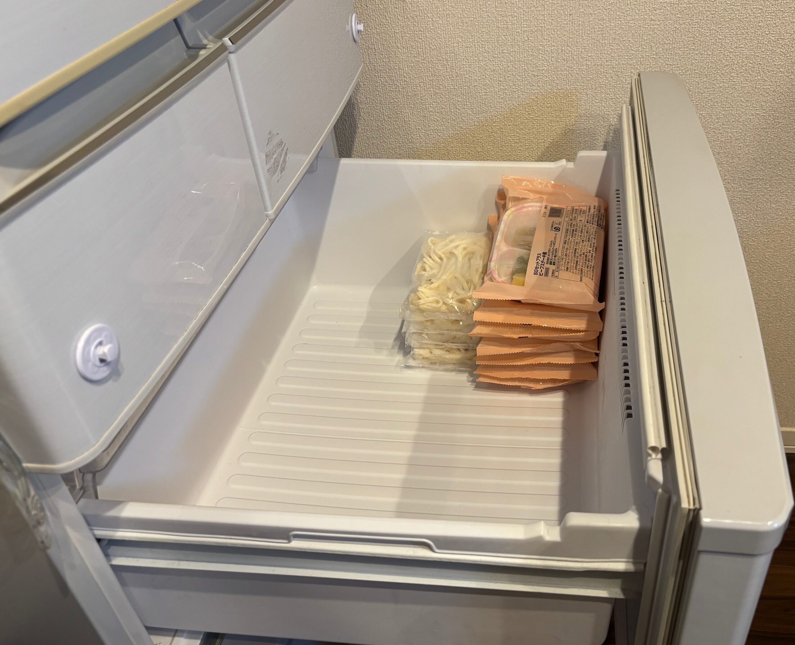 食楽膳のムース食を家庭用冷凍庫に冷凍うどんと一緒に収納した様子を横から撮った写真