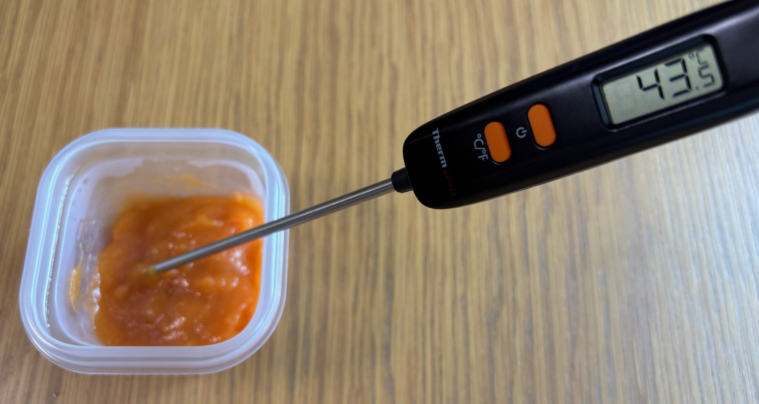 電子レンジで温めたにんじんのムース食。温度計は43.5℃を示し、食べごろのやわらかさになっている