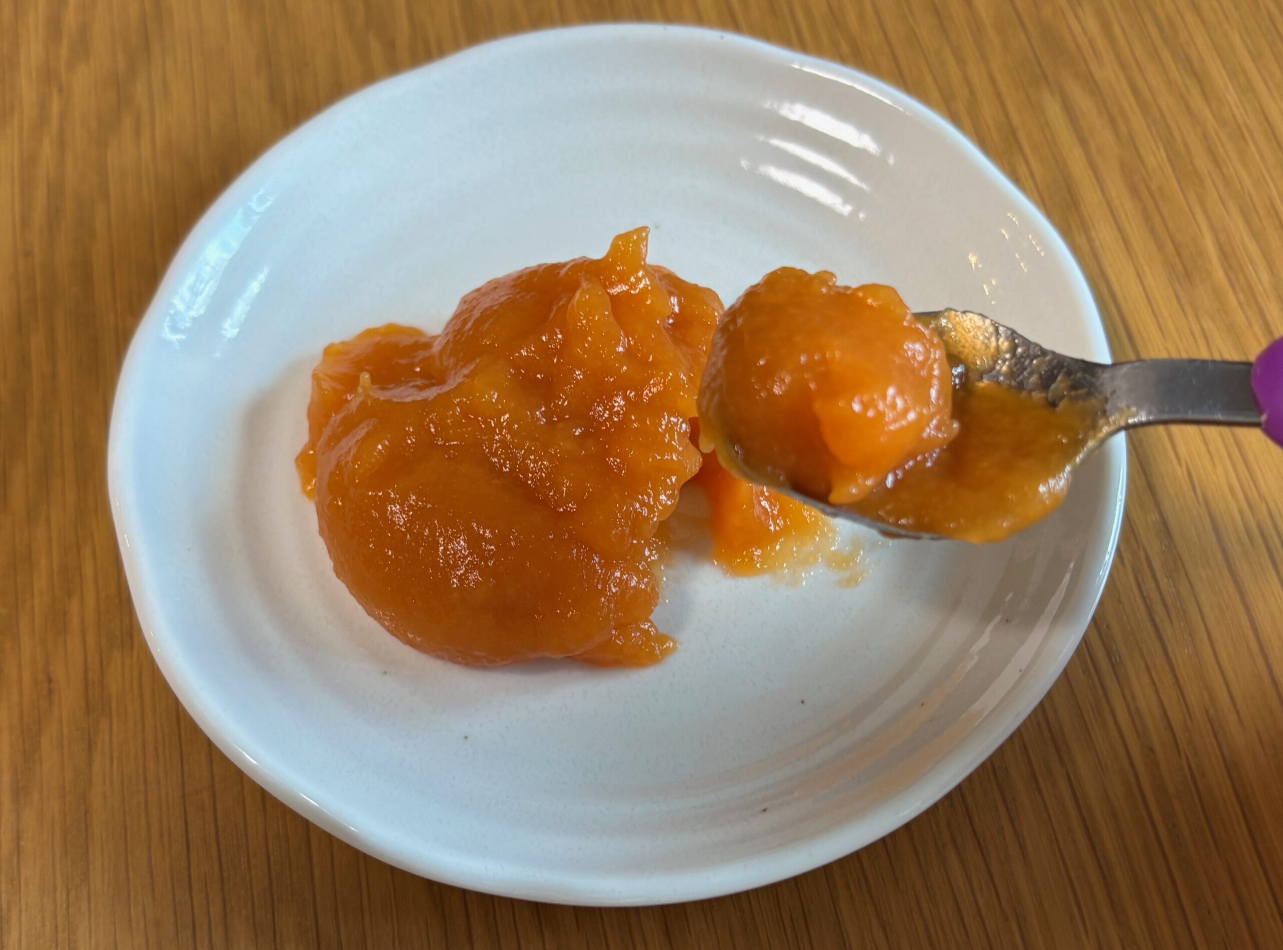 湯せんで温めたにんじんのムース食を小皿に出し、スプーンですくっているところ