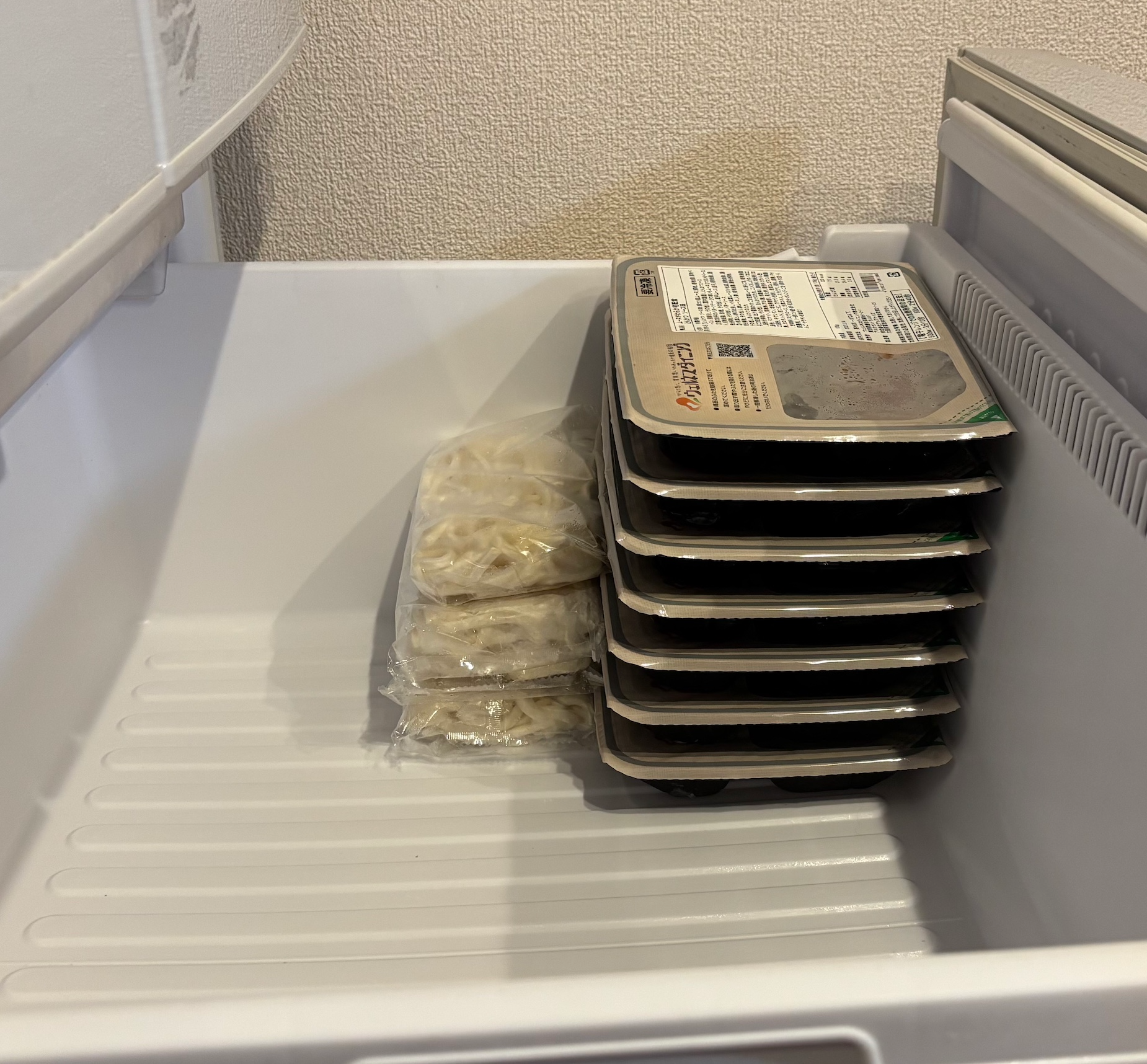 家庭用冷凍庫にウェルネスダイニングのムース食と冷凍うどんを並べて入れた写真