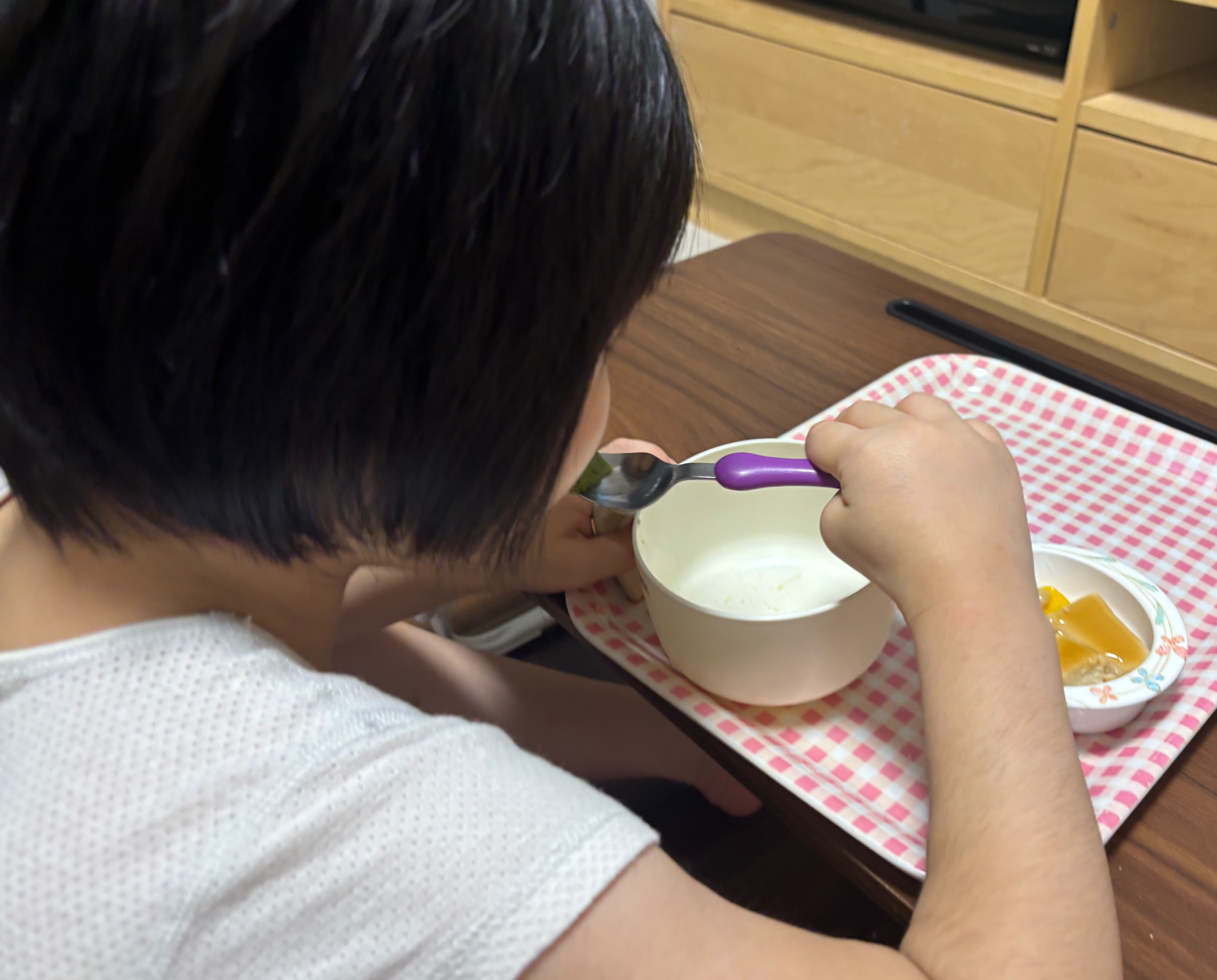 娘がスプーンでいんげんのムースをすくって食べているところ