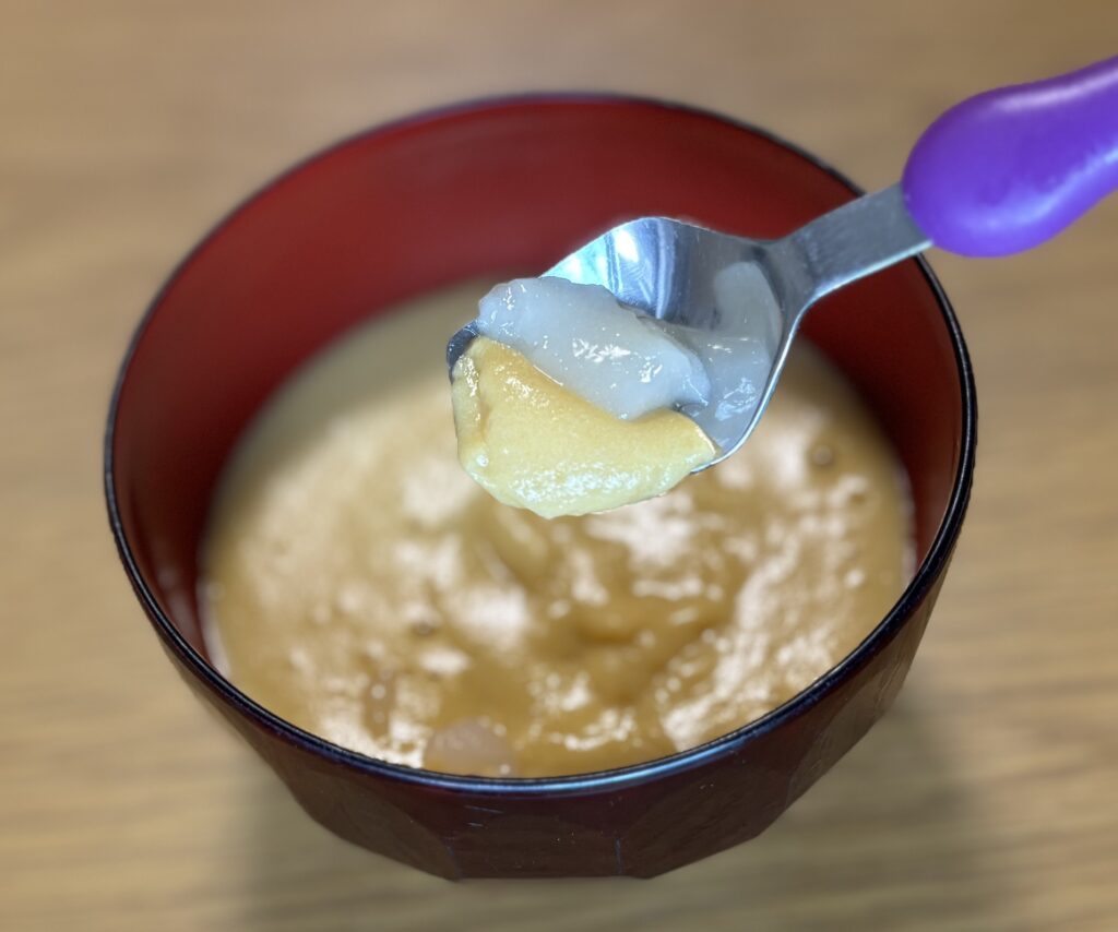 スプーンの上に、ムースのお雑煮とスプーンで食べるおもちを一口分すくったところ