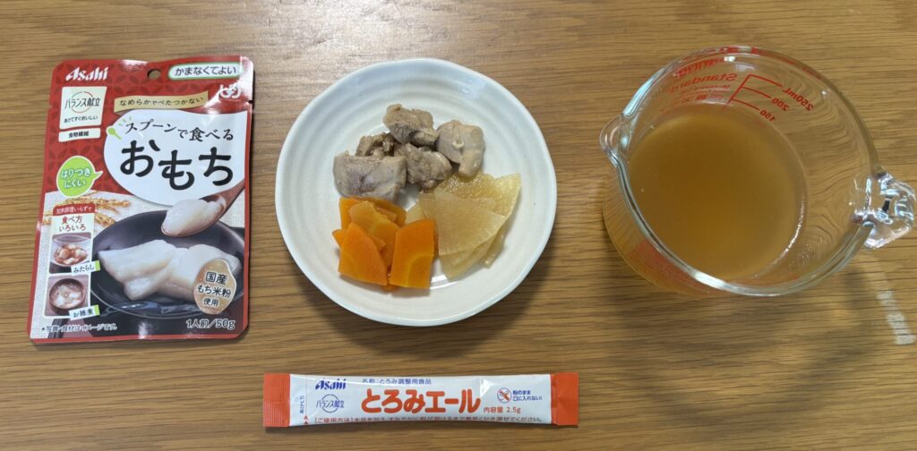 刻みのお雑煮の材料。スプーンで食べるおもち、一口大の鶏もも肉・人参・大根、だし汁、とろみエール1本