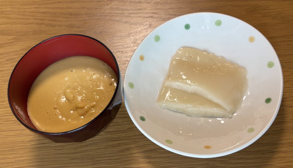 汁椀に盛ったムースのお雑煮と、別皿に出したスプーンで食べるおもち