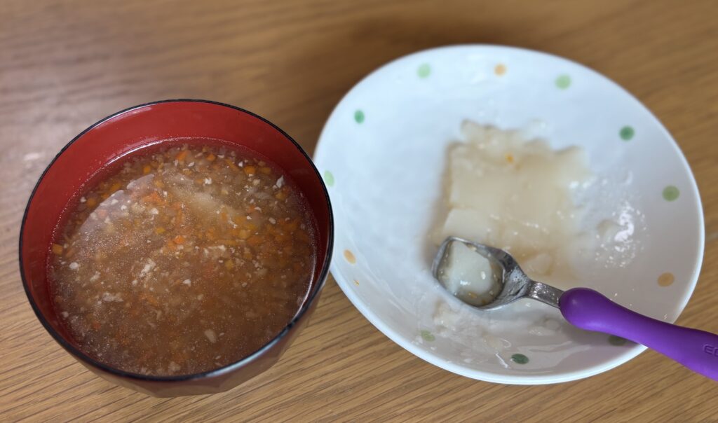 汁椀に盛った刻みのお雑煮と、別皿に出したスプーンで食べるおもち。小皿にはスプーンが添えてある